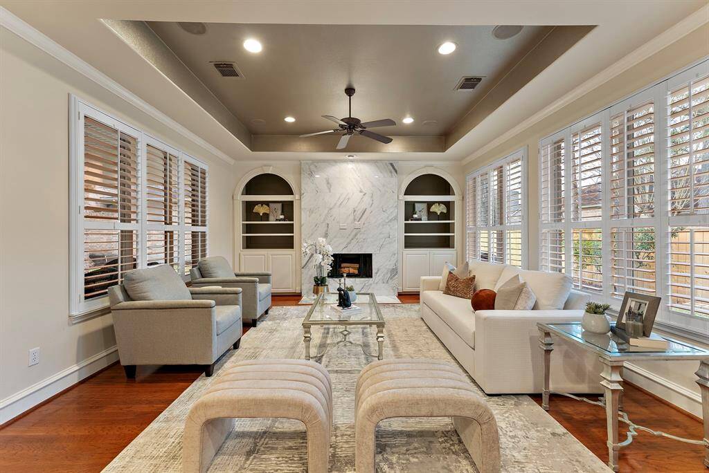 The living area boasts hardwood floors and abundant natural light from expansive windows. High ceilings enhance this open, airy space, ideal for both relaxation and entertaining. A marble fireplace anchors the room, offering elegance and functionality in a thoughtfully designed layout.