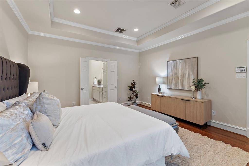 This spacious primary suite offers plenty of room for additional seating and showcases a seamless flow into the ensuite bath. Soft, neutral tones create an atmosphere of serene sophistication, making it the perfect retreat for restful evenings.