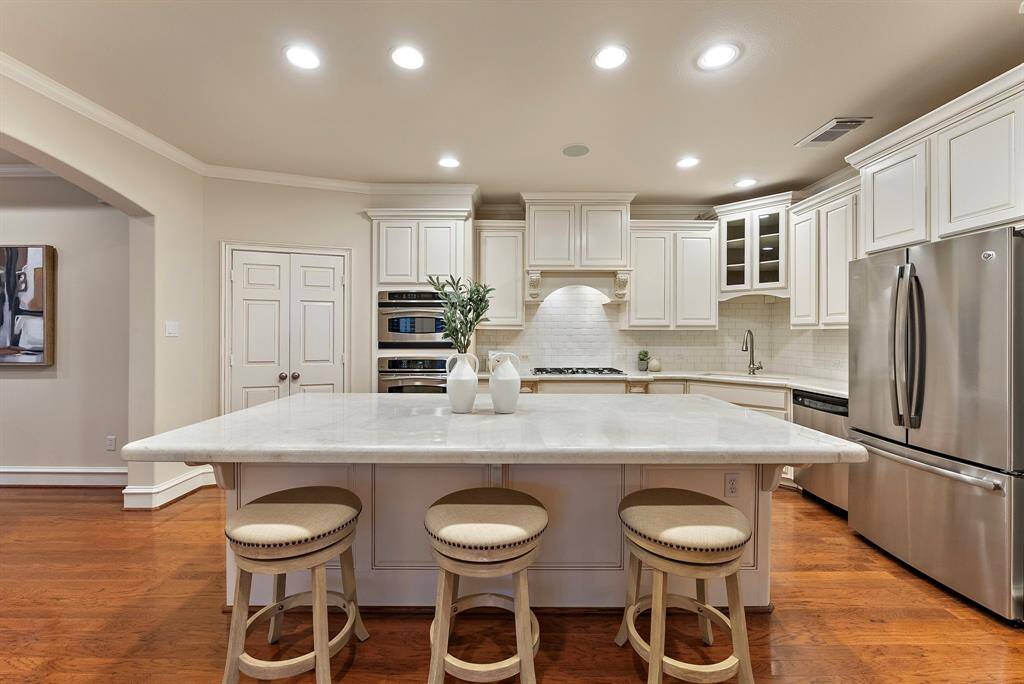 Create culinary delights in this remodeled kitchen featuring an oversized island, modern backsplash, and ample storage. An ideal hub for gatherings, it seamlessly integrates with the home's open layout, offering convenient access to the pantry, casual breakfast area and the outdoor patio.