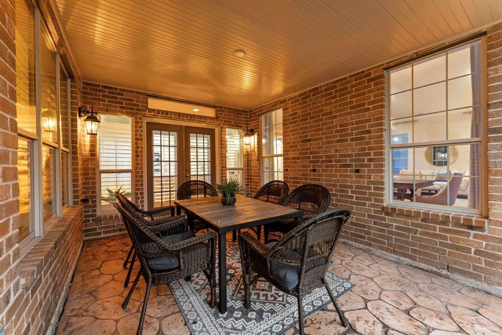 The inviting covered patio showcases stamped concrete flooring and warm brick accents, creating an ideal spot for year-round entertaining.