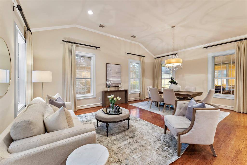 Discover an inviting formal living area with abundant natural light from large windows, set against elegant hardwood floors. The open-concept design flows effortlessly into the dining area, creating a seamless space ideal for entertaining and everyday living.