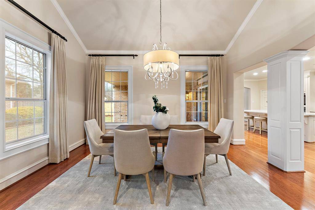 The dining area is filled with natural light from large windows, highlighting the warm hardwood flooring. Its open layout easily accommodates a large dining table, making it perfect for gatherings.