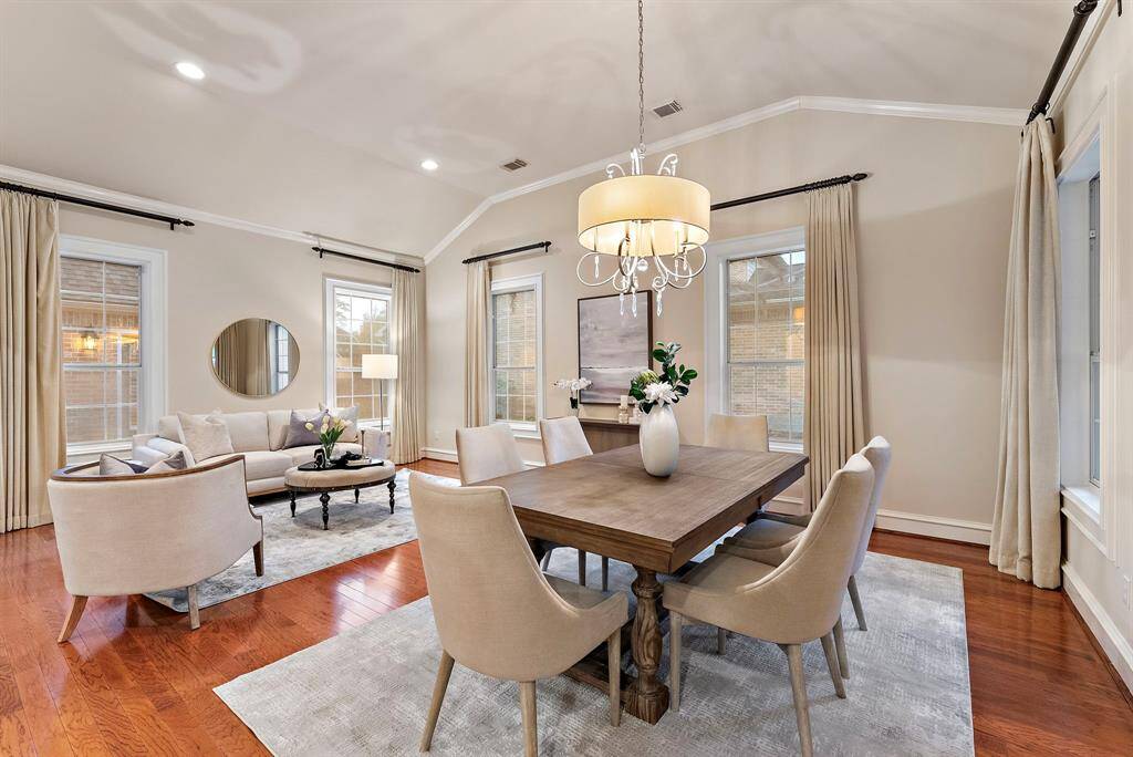 This spacious dining and living areas offer soaring ceilings and expansive windows, allowing natural light to flood the space. With hardwood floors and room for a spacious dining table, it seamlessly connects to a welcoming living area designed for comfort and style.