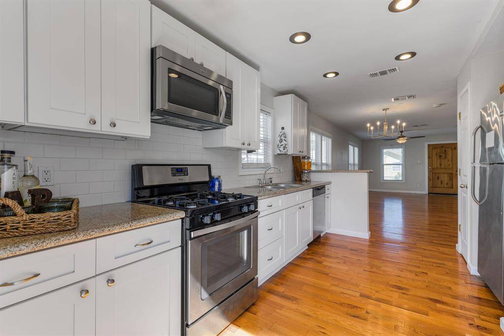 Modern kitchen with sleek appliances, elegant cabinetry, and rich hardwood floors.