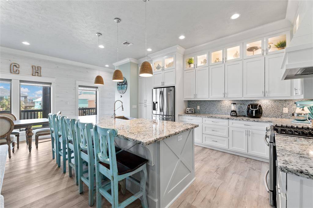 The oversized kitchen island offers ample counter space, additional seating, and stylish designer pendant lighting. Whether prepping meals or enjoying a casual bite, this space is both functional and inviting.