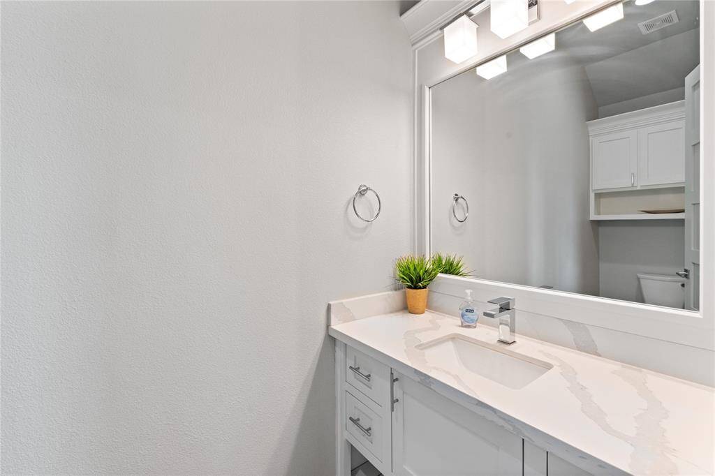 This stylish half bath off the living room features sleek quartz countertops, designer fixtures, and ample lighting, offering both convenience and elegance. Perfect for guests, this thoughtfully designed space blends seamlessly with the home’s modern coastal aesthetic.