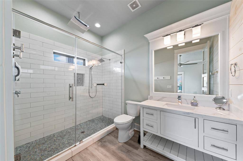 Step into a spacious walk-in shower featuring dual shower heads and sleek modern finishes. Designed for relaxation, this spa-inspired ensuite offers a serene escape after a day at the beach.