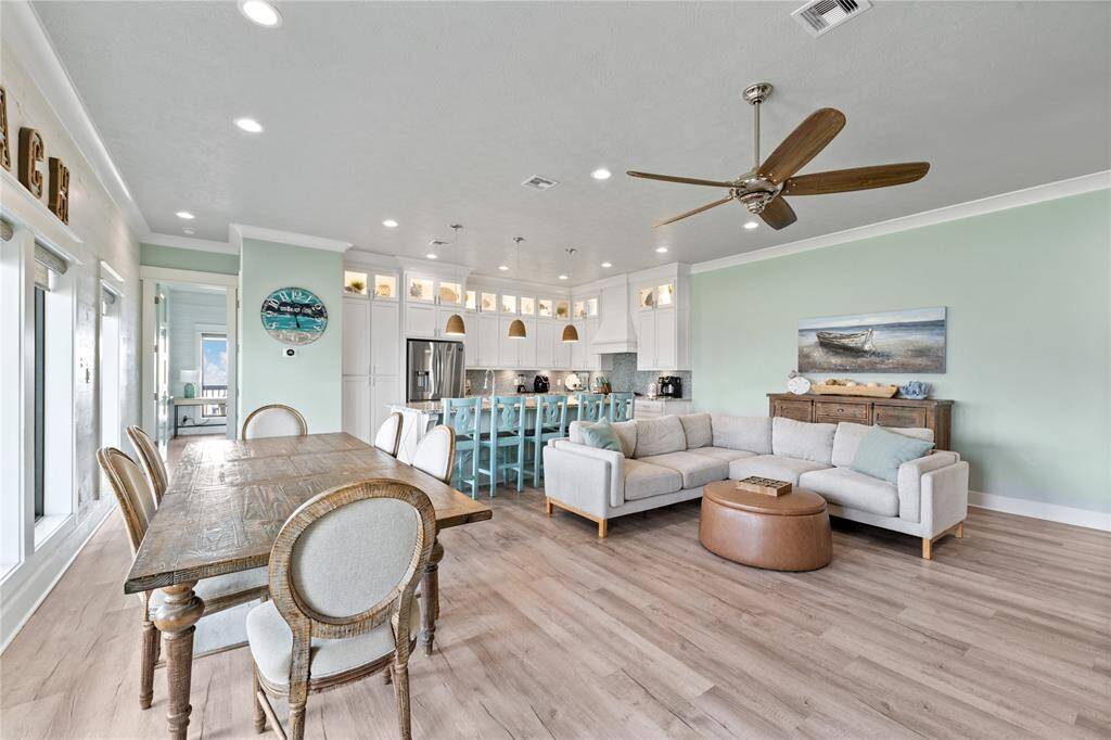 Step into a stunning open-concept living space where the kitchen, dining, and family room flow seamlessly together. Vaulted ceilings and oversized windows flood the room with natural light, creating a warm and inviting coastal retreat.