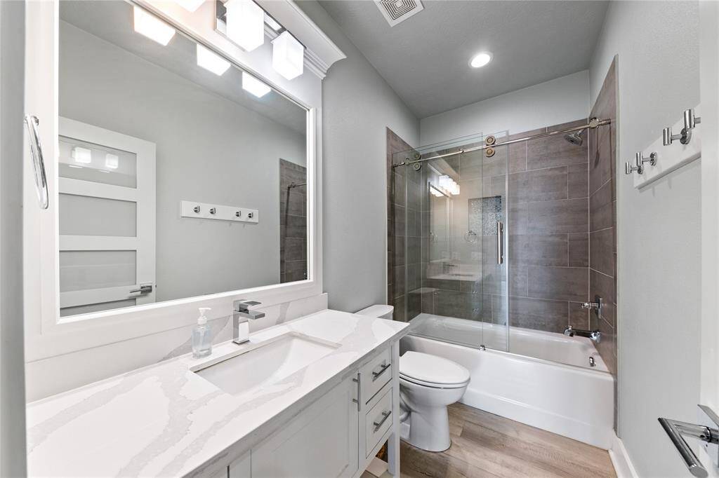 This shared secondary bathroom features a convenient tub-shower combo, perfect for both relaxing baths and quick showers. With sleek finishes and ample storage, it’s a practical yet stylish space for family or guests.