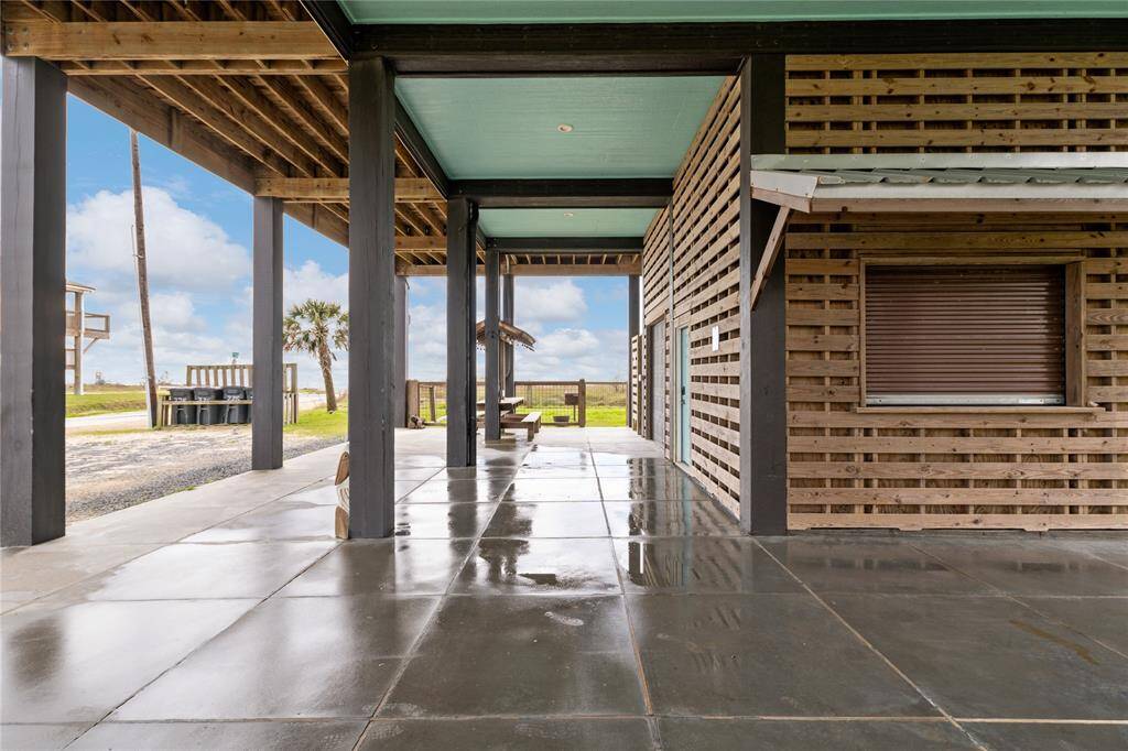 The downstairs area features a built-in picnic table for outdoor dining, a fully fenced yard for privacy, and an outdoor shower to clean off after a day at the beach—all under the comfort of a covered space with easy storage access.