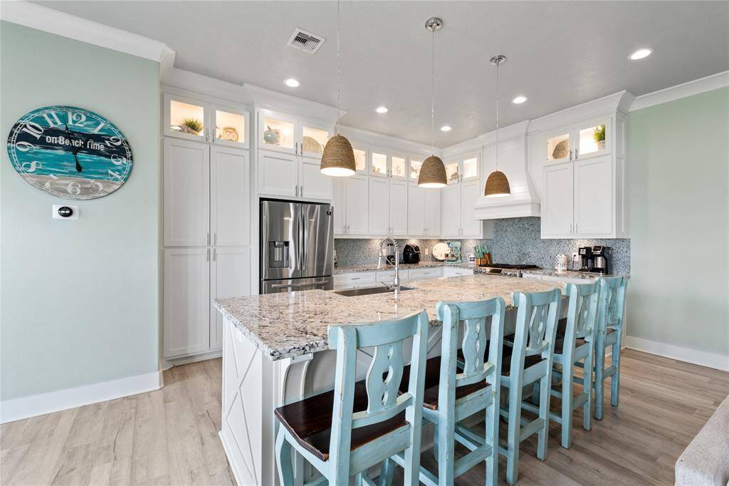 Soft under-cabinet lighting enhances the kitchen’s ambiance, highlighting the stunning quartz countertops and ensuring a well-lit workspace for meal prep. A perfect blend of style and function