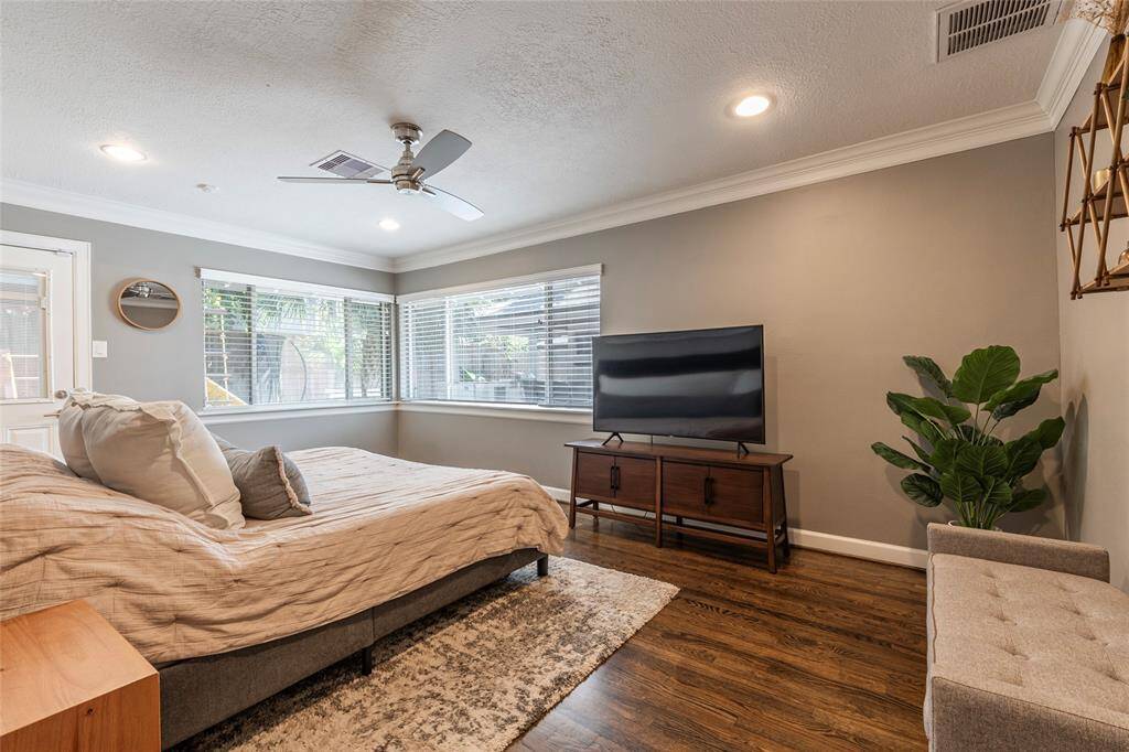 This cozy bedroom features a spacious layout with a large window offering natural light, a ceiling fan for comfort, and hardwood floors. Your plush bed and stylish decor will create a welcoming and relaxing atmosphere.