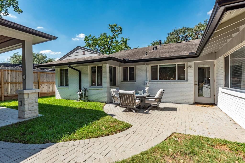 This charming backyard patio area features a paved patio with outdoor seating, surrounded by a well-maintained lawn and wooden fencing. A welcoming and serene setting for outdoor relaxation.