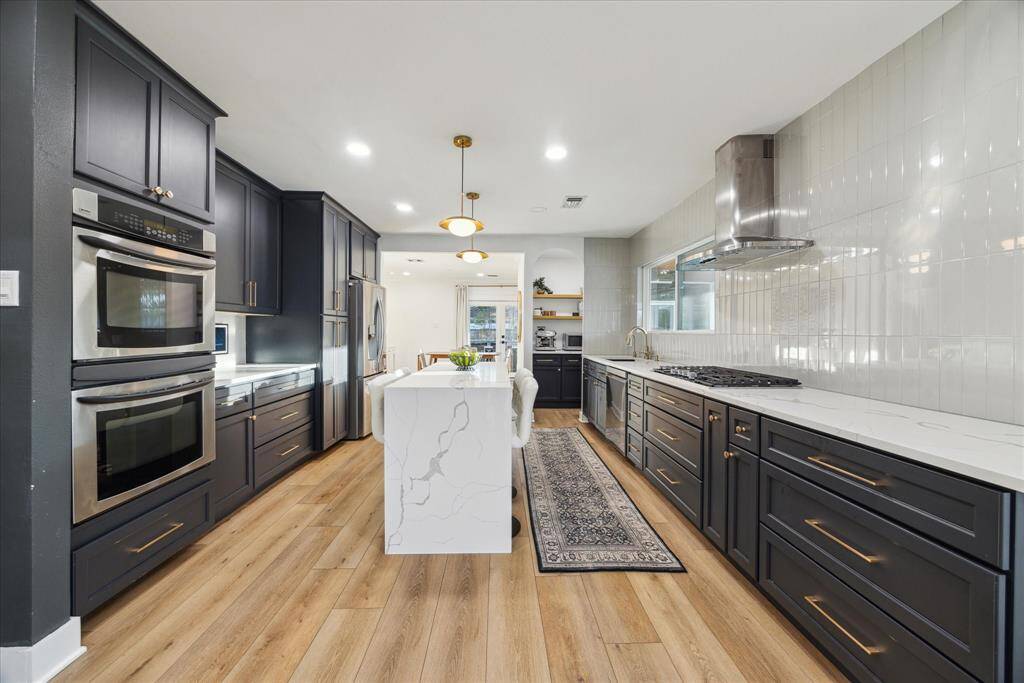 Renovated kitchen features waterfull island, quartz counters, updated soft close cabinets, 5-burner gas range, walk-in coffee bar