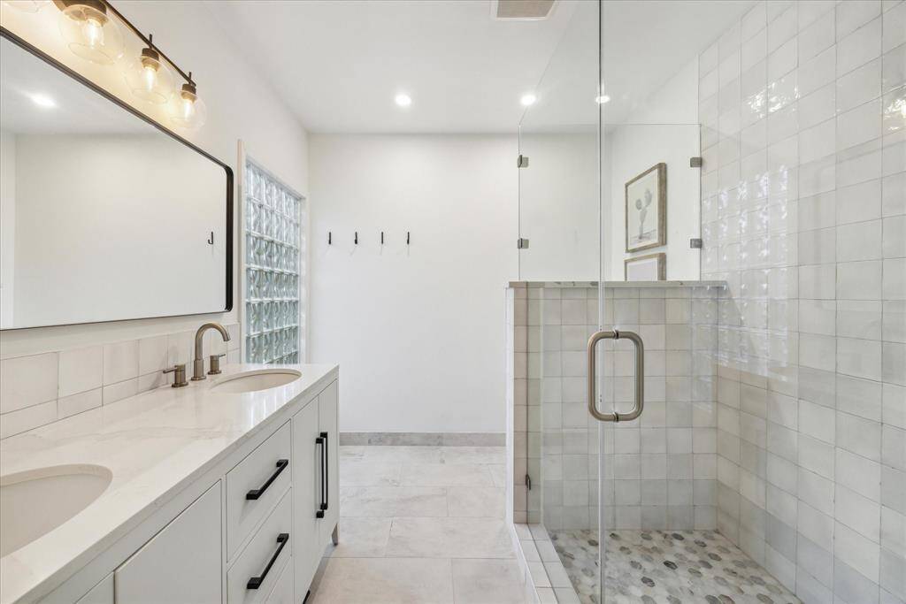 Talk about a transformation...This primary bathroom has been completely renovated: floors, stunning walk-in shower, & a sleek double-sink vanity