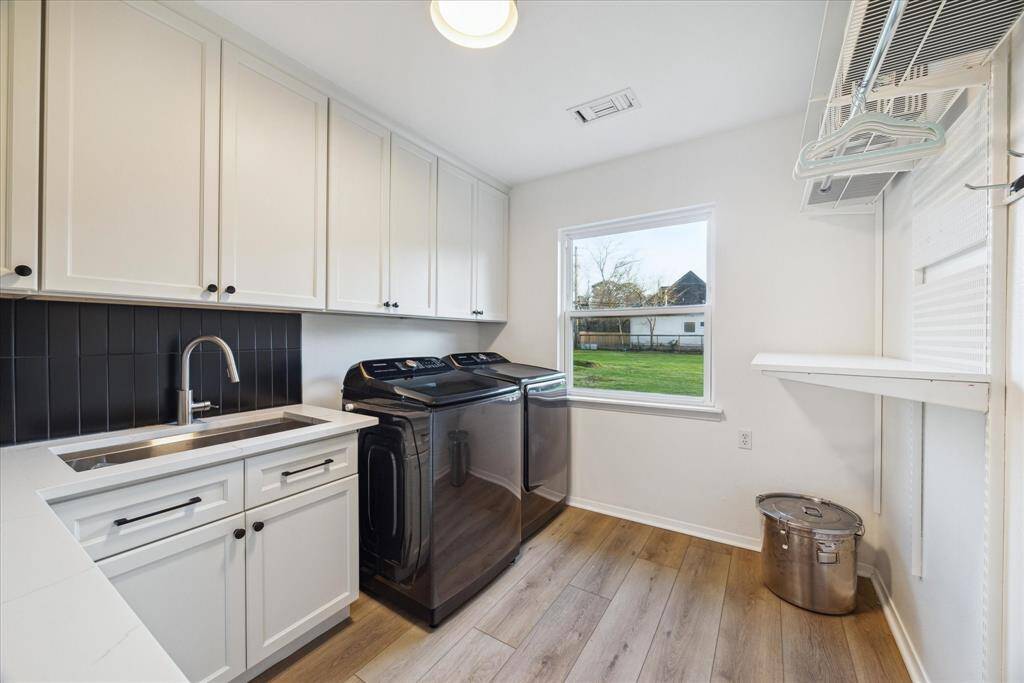 The utility room features custom-built cabinets and large sink providing amazing storage for all of your kids + furry friends