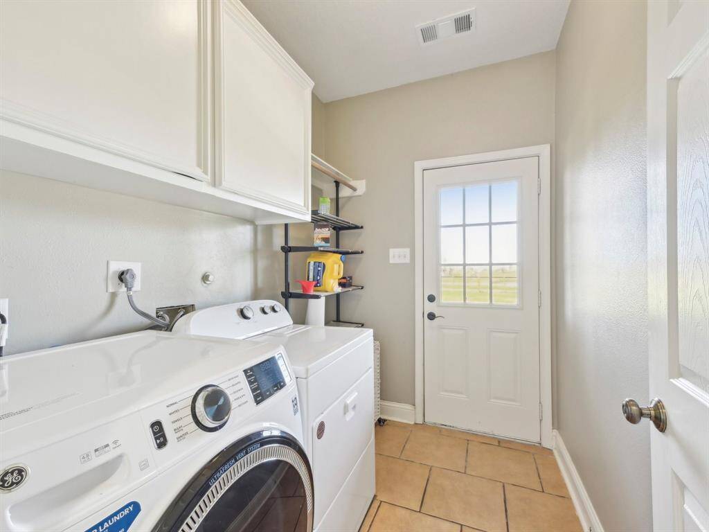 This spacious laundry room has cabinetry and shelving for all your cleaning essentials.