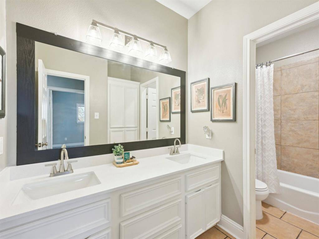 The Secondary Bathroom has double sinks and a pretty, framed mirror.