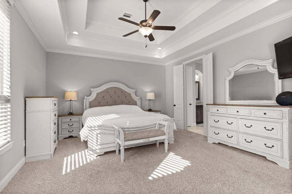 Primary bedroom featuring tray ceiling detail and ample natural light.