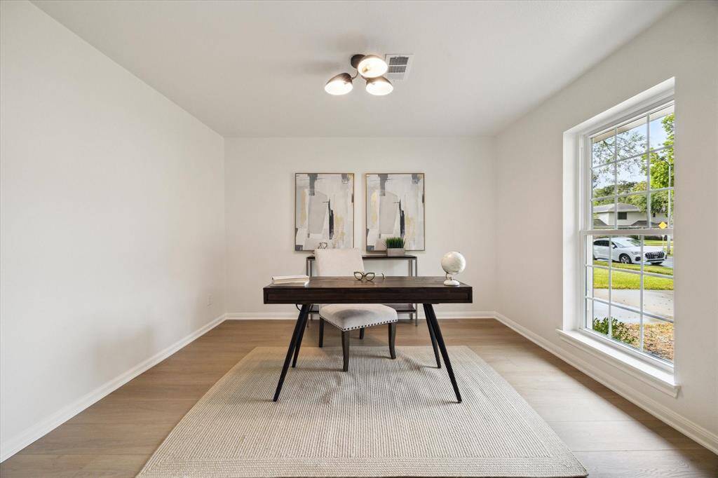 THE STYLISH HOME OFFICE FEATURES LARGE PICTURE WINDOW ALLOWING IN PLENTY OF NATURAL LIGHT. NOTICE THE LUXURY VINYL PLANK FLOORING CONTINUES THROUGHOUT THE MAIN LIVING AREAS.