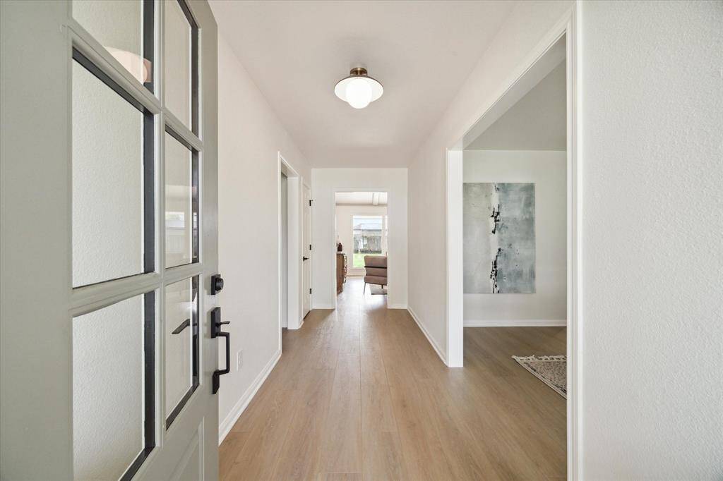 THE RECENT FRONT DOOR IS HANDSOME WITH GLASS PANES AND OPENS UP TO THE ENTRANCE HALL FEATURING DESIGNER "EVERGREEN" LUXURY VINYL PLANK FLOORING.
