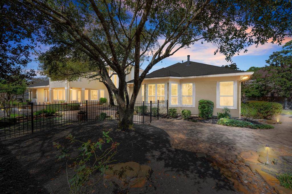 Experience serene elegance with this home's beautifully lit back elevation at dusk, showcasing a spacious yard and inviting ambiance.