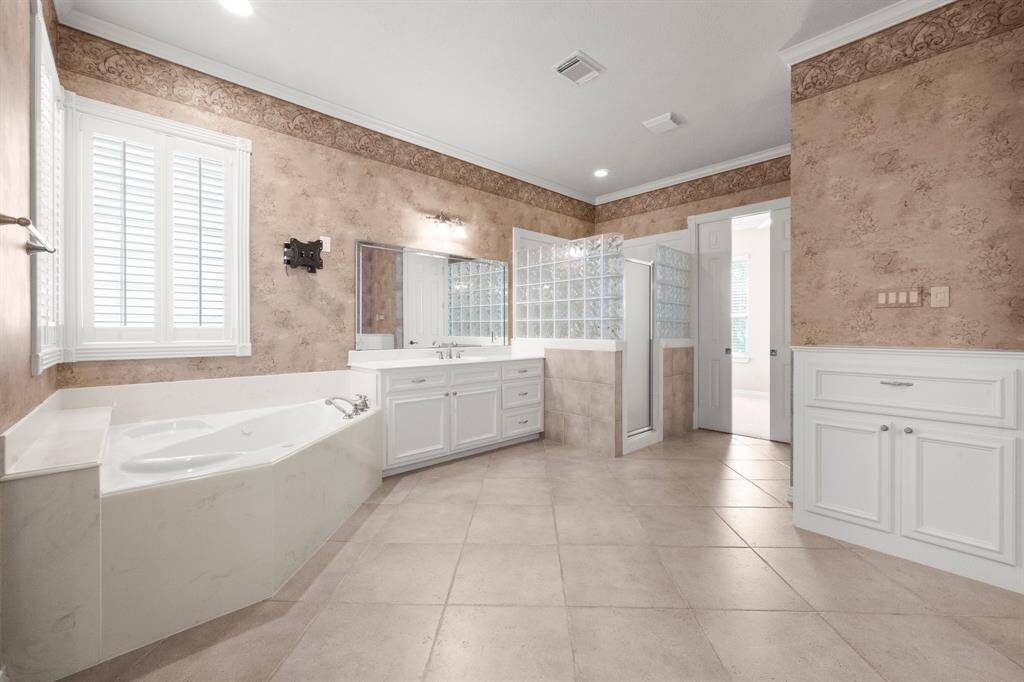 Luxurious bathroom featuring a walk-in shower, a relaxing tub, and spacious his-and-her closets.