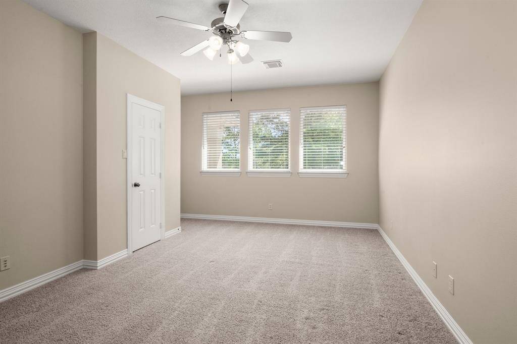 Bright, spacious bedroom that features a ceiling fan and lots of natural light.