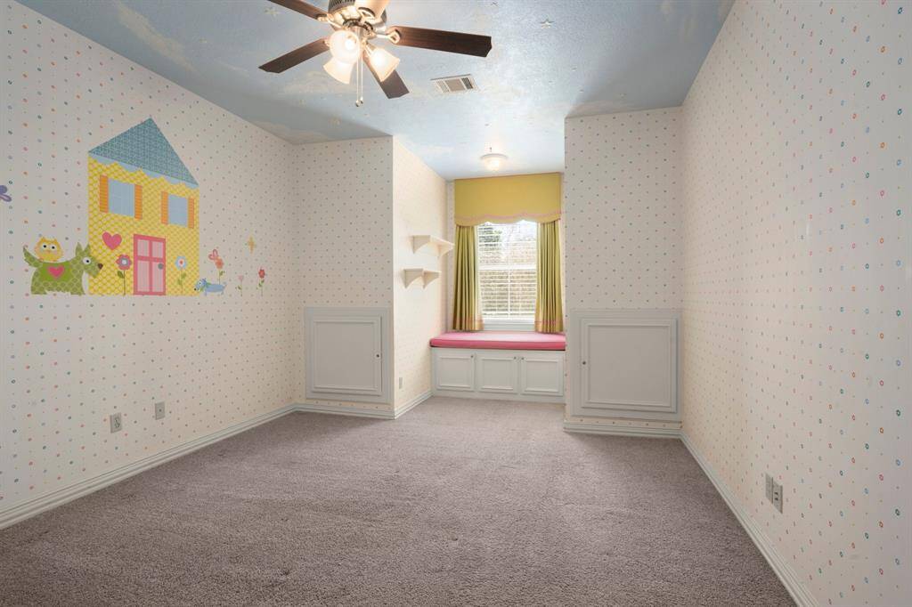 This bedroom features a big window with sitting nook that makes it a vibrant space ideal for a child's bedroom or playroom.