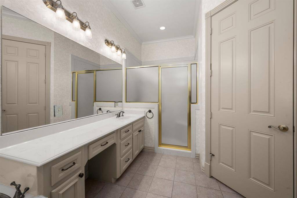 The casita bathroom features a long vanity with ample storage, a large mirror, and modern lighting. It includes a shower with frosted glass offering a sleek and functional design. Walk-in closet also provides extra storage.