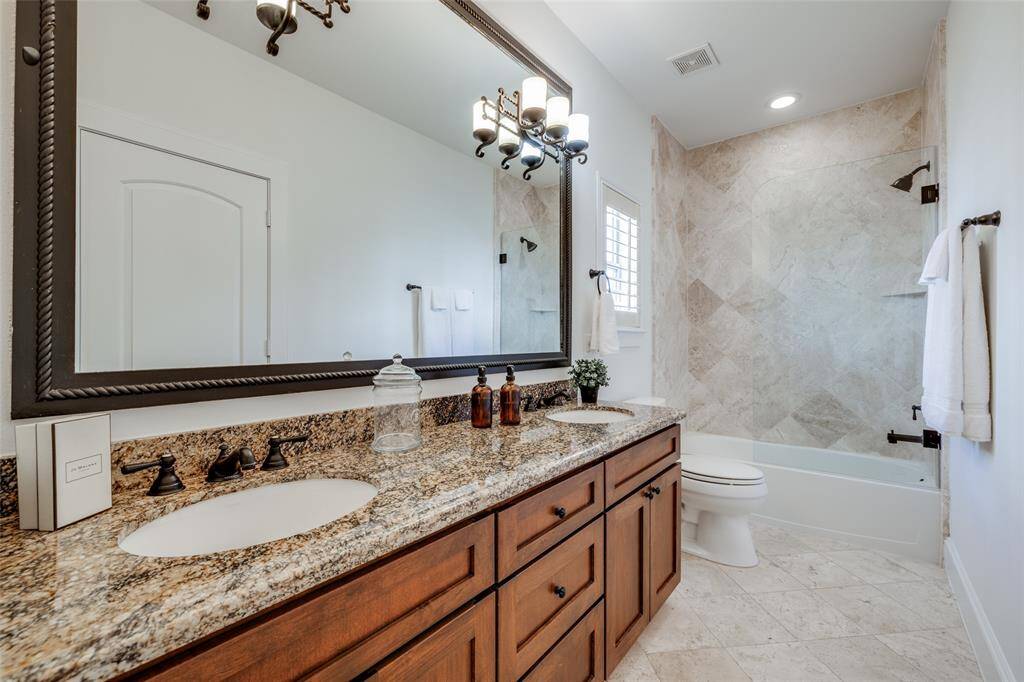 Large Jack & Jill Bathroom on second floor with bath, travertine tile, double vanities, large mirror, oil rubbed bronze fittings, seamless glass shower door