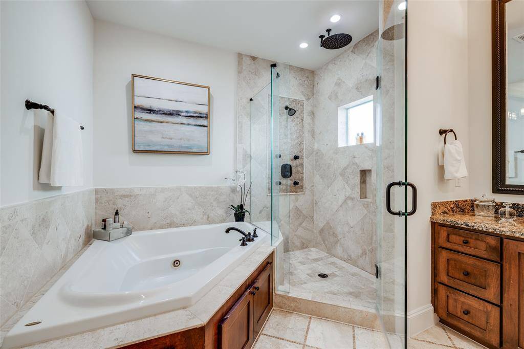 Fabulous luxury Primary Bathroom with large corner Jacuzzi bath, large shower with seamless glass surround, beautiful travertine tile, rain head & shower head & body jets, storage nook, window for lots of natural light