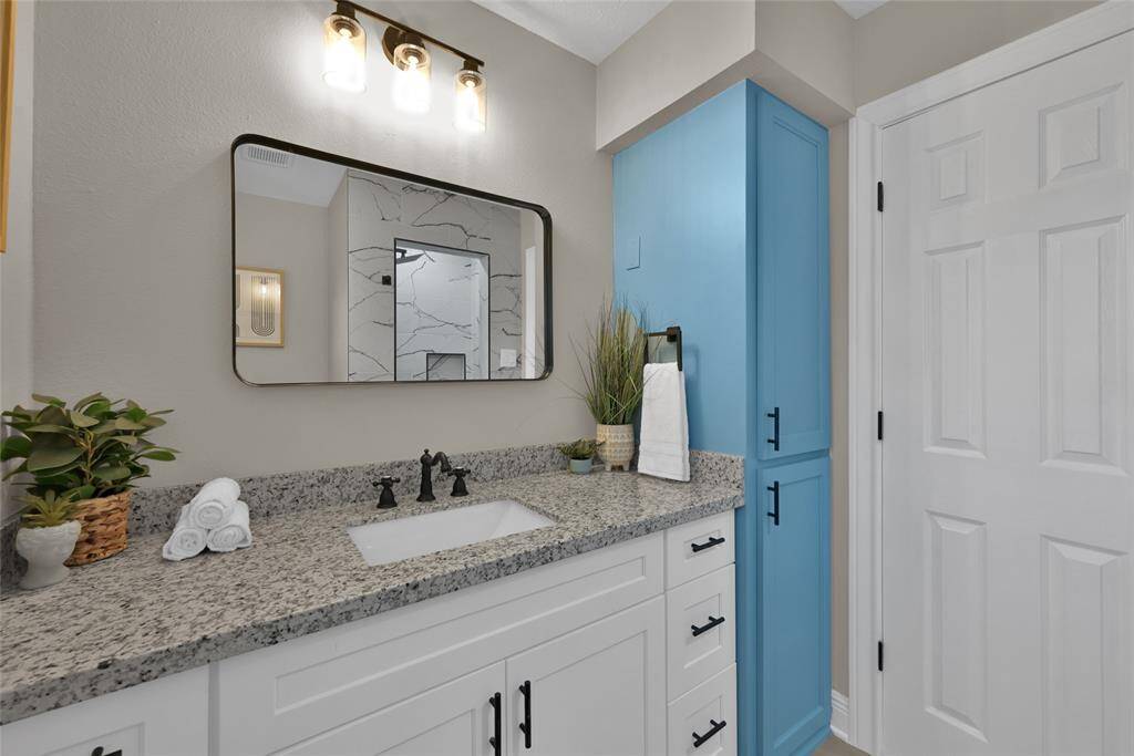 The vibrant blue motif continues into the primary bathroom. Granite countertops and modern finishes complete the primary retreat.