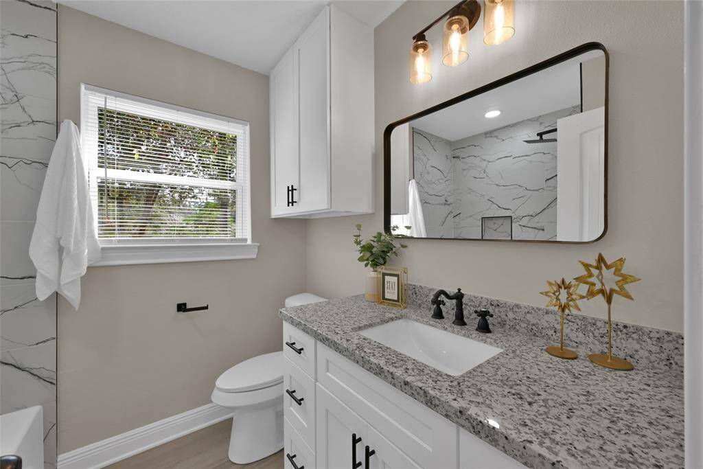 The secondary full bathroom with crisp white cabinets and a gorgeous granite countertop.