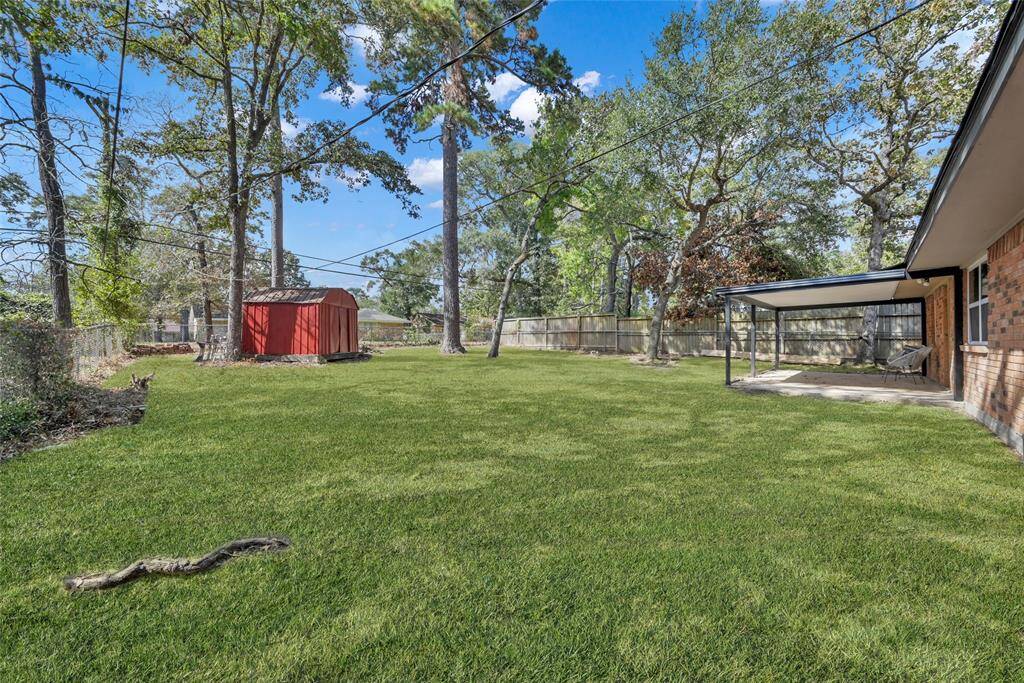 The large backyard features features mature trees, a storage shed, and a spacious covered back patio for entertaining or relaxation.
