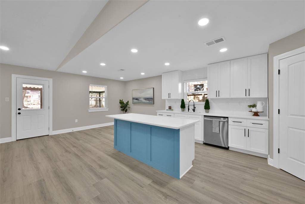 Sleek white cabinetry and modern finishes set the stage for culinary creativity. The striking blue island provides a nice accent.