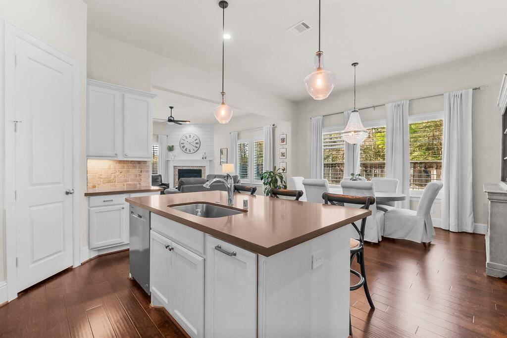 Open-concept kitchen features an island with large sink, pendant lighting and breakfast bar. The dining area adorned with large windows and views of the backyard.