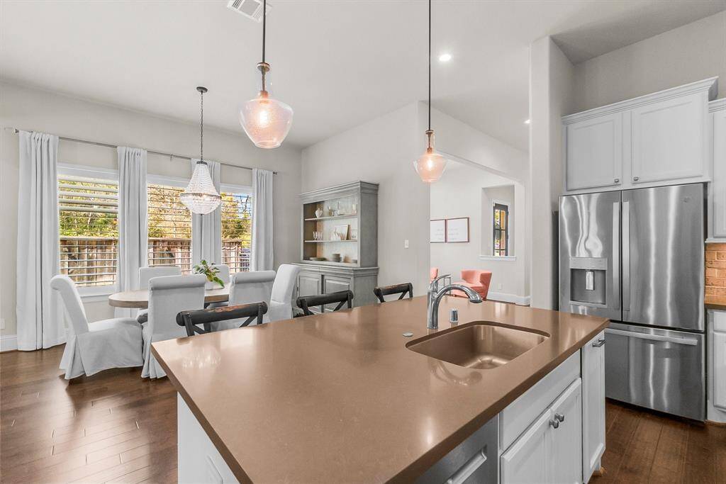 Bright kitchen and dining area with modern lighting fixtures, hardwood floors and large windows. Refrigerator with french doors and freezer drawer is included.