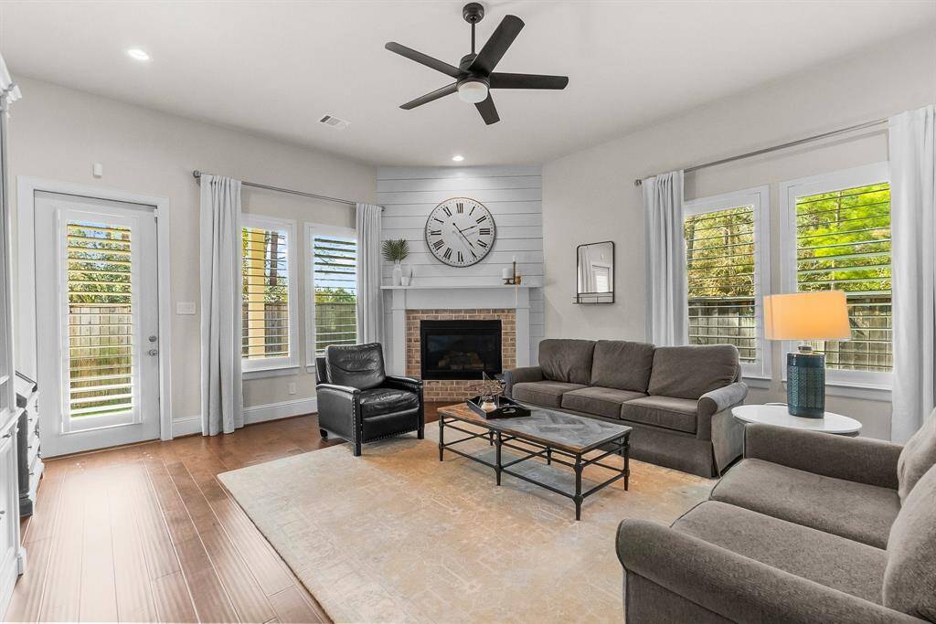 Living area with corner gaslog fireplace and ample natural light from multiple windows.  Glass door leads to the covered porch creating a perfect space for relaxation and entertaining.