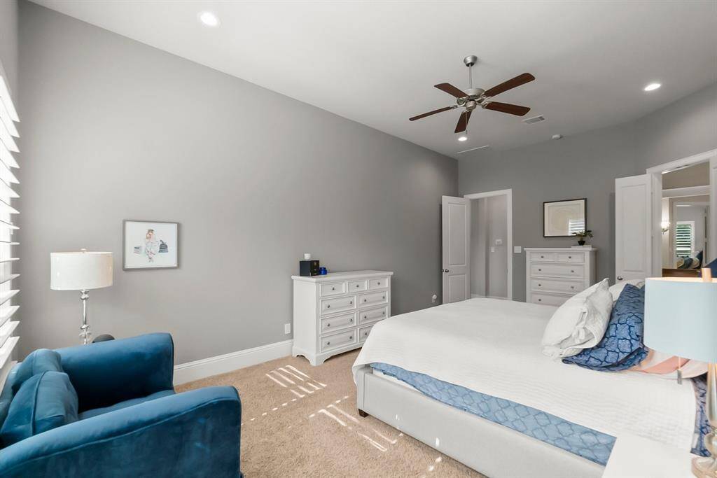 Primary bedroom features soft gray walls, a ceiling fan, and ample natural light creating a serene and comfortable ambiance.