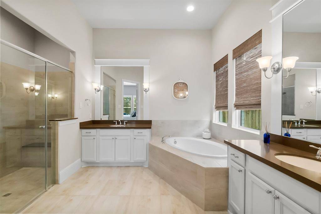 Primary bathroom features a glass walk-in shower, dual sinks, a central soaking tub, and natural lighting.