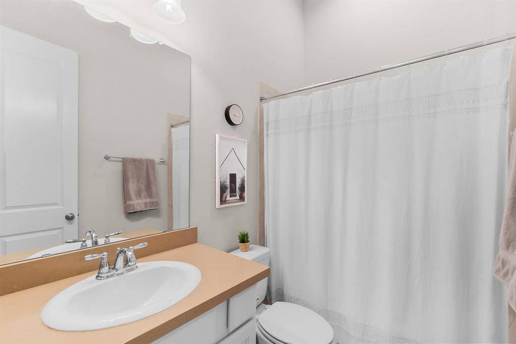 Private bathroom to second bedroom features a clean, modern design with a large mirror, and a shower-tub combo.