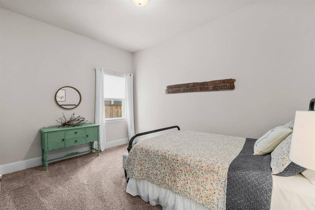 Fourth bedroom features neutral walls, carpeted flooring, and a large window for natural light.
