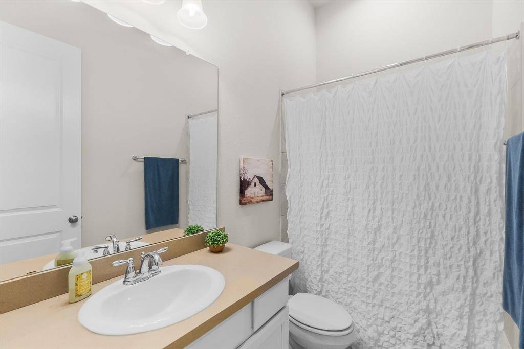 Third bathroom featuring a single sink vanity with a large mirror, white cabinetry and shower/tub combo.