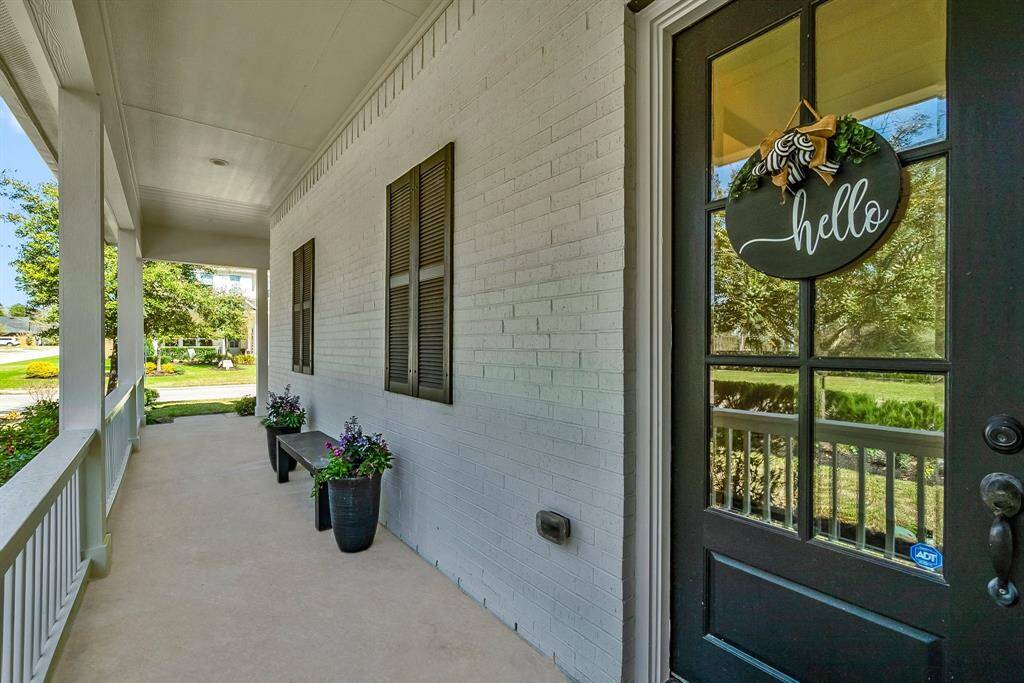 Spacious front porch, ideal for cozy furniture and terracotta flower pots.  The white brick exterior and dark door and plantation shutters create a classic style.