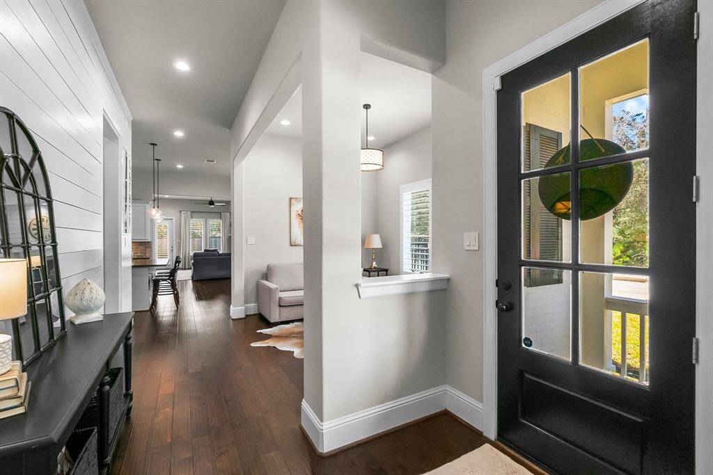Foyer leads into an open-concept living area with hardwood floors, modern lighting, and a cozy seating space.