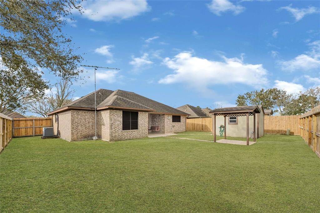 Large fenced backyard featuring a shed for all your storage needs.