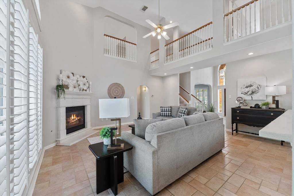 Spacious vaulted ceiling living room with gas log fireplace, shutters, and recent paint.