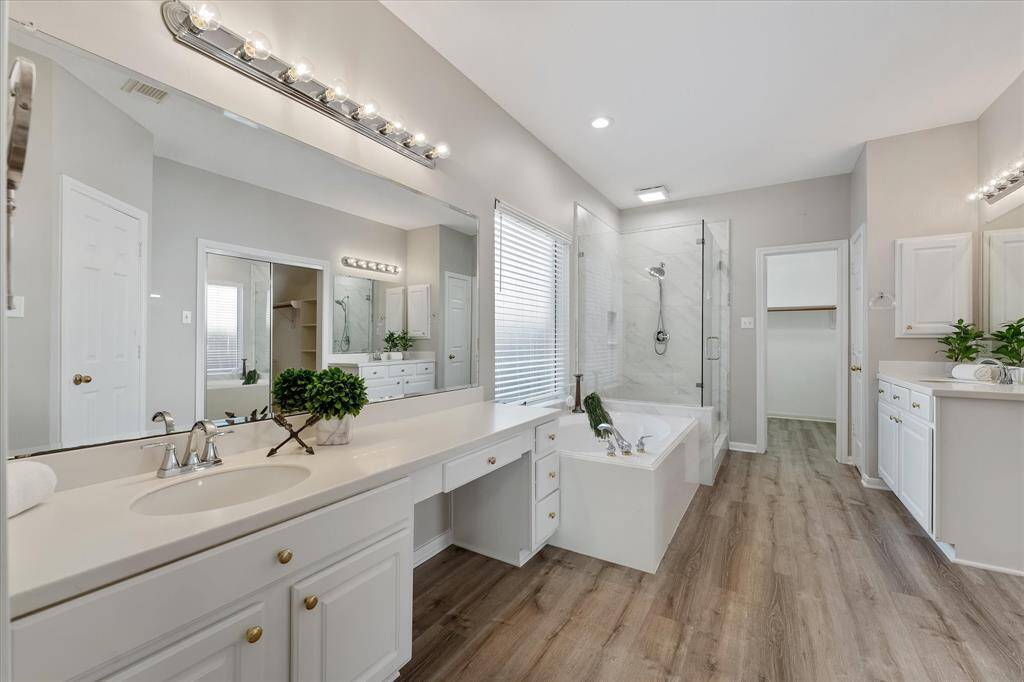 Ensuite primary bath with TWO walk in closets, double vanities freshly painted, and updated step in shower with frameless shower door.