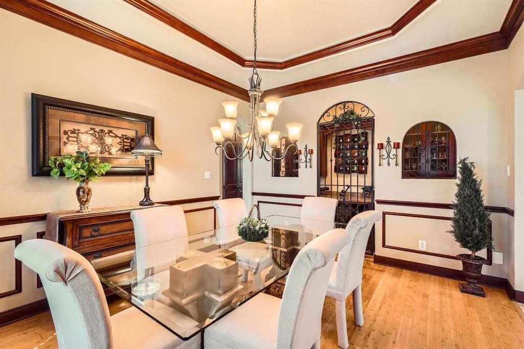 This elegant dining room features warm wood accents and a stylish chandelier. A built-in wine rack with decorative wrought iron adds charm.